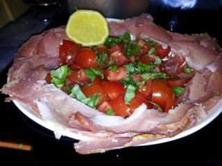 Piatto di prosciutto crudo con insalata di pomodoro con basilico fresco